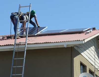 Personas instalando panel solar sobre un techo