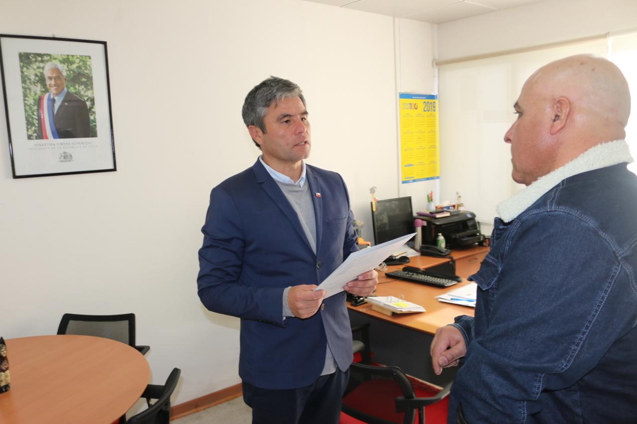 Se aprecia trabajador accidentado conversando con el Seremi de vivienda antes de recibir el carton que simboliza la entrega del beneficio